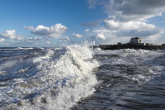 Waves breaking over the pier at Amble, Northumberland Coast.