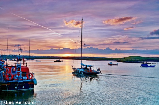 Yacht sailing up the River Coquet at sunset.
