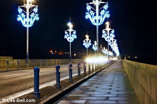 View along the Royal Tweed Bridge at night with Xmas lights on the lamp posts.