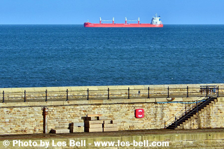 Cargo ship moored off the coast near the entrance to the River Tyne at Tynemouth Pier.